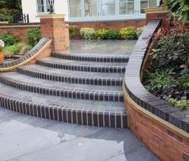 Curved brick steps with lush greenery.